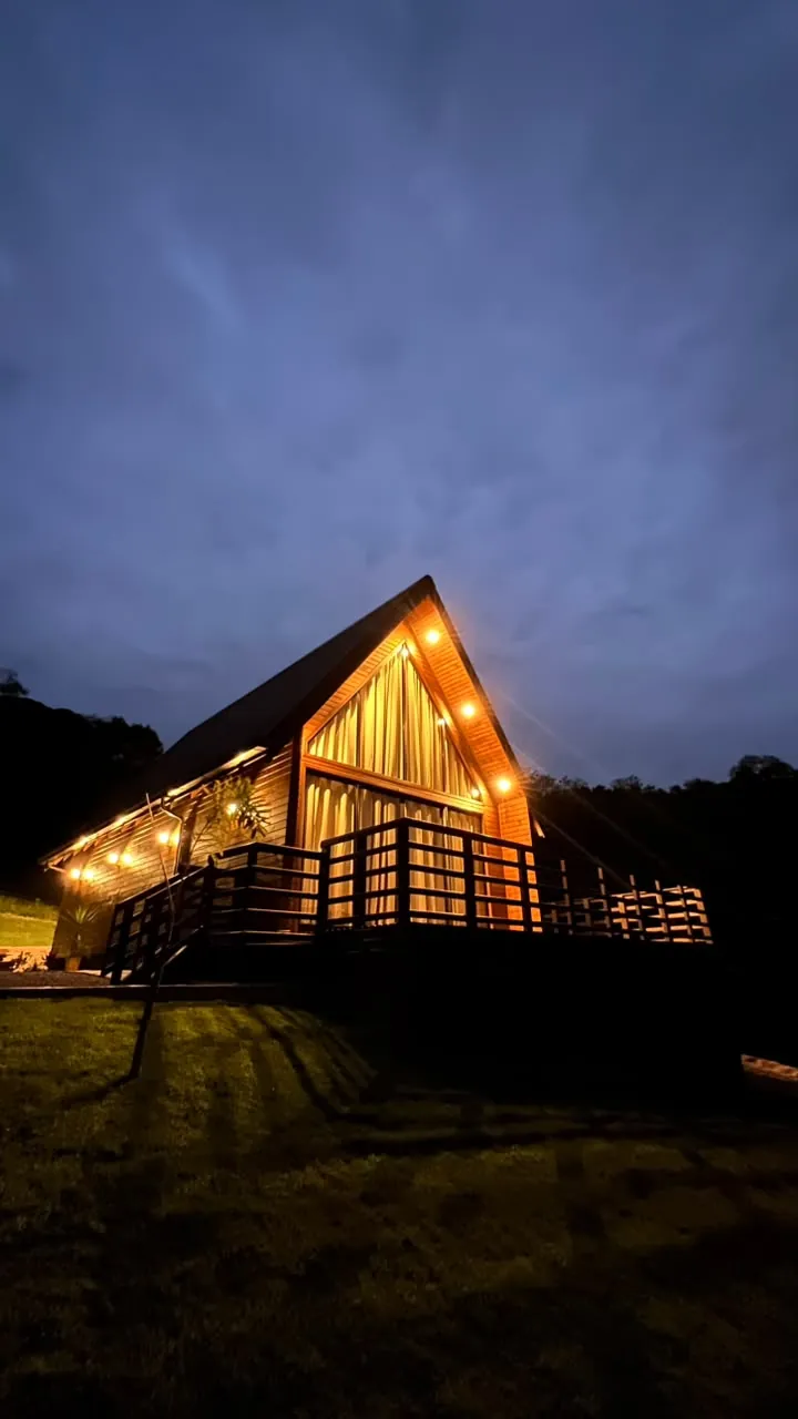 O chalé na hora azul, com as luzes do deck e do beiral acesas