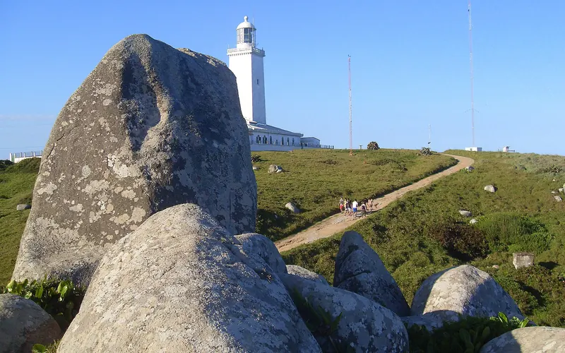 O farol branco de Santa Marta no alto do morro, com grandes pedras em primeiro plano