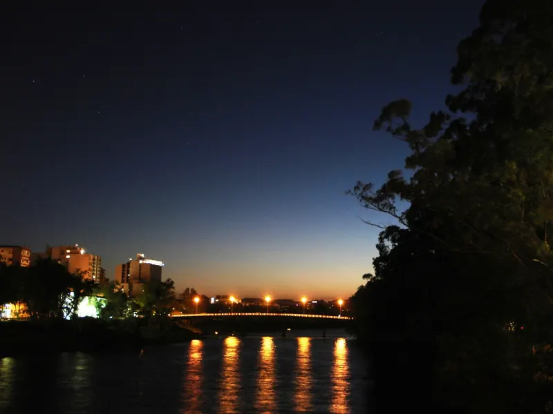 O rio Tubarão ao entardecer, com as luzes de uma ponte refletidas na água